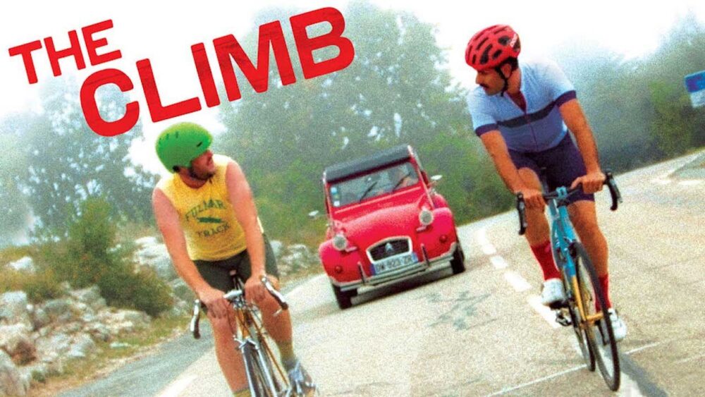A still from the Sony Pictures Classics movie THE CLIMB depicting two actors biking up a hill while talking.