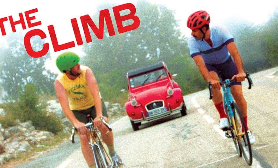 A still from the Sony Pictures Classics movie THE CLIMB depicting two actors biking up a hill while talking.