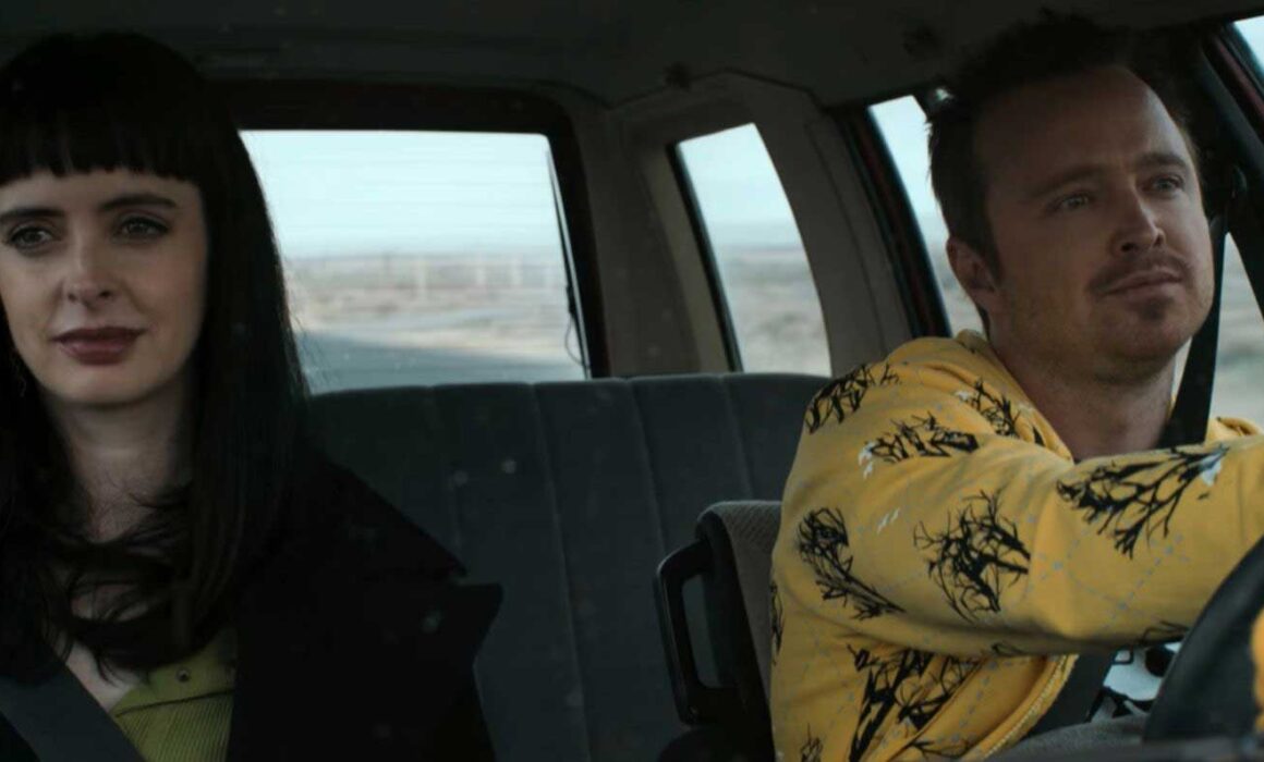 A still from the movie El Camino featuring Aaron Paul and Krysten Ritter driving in a car.